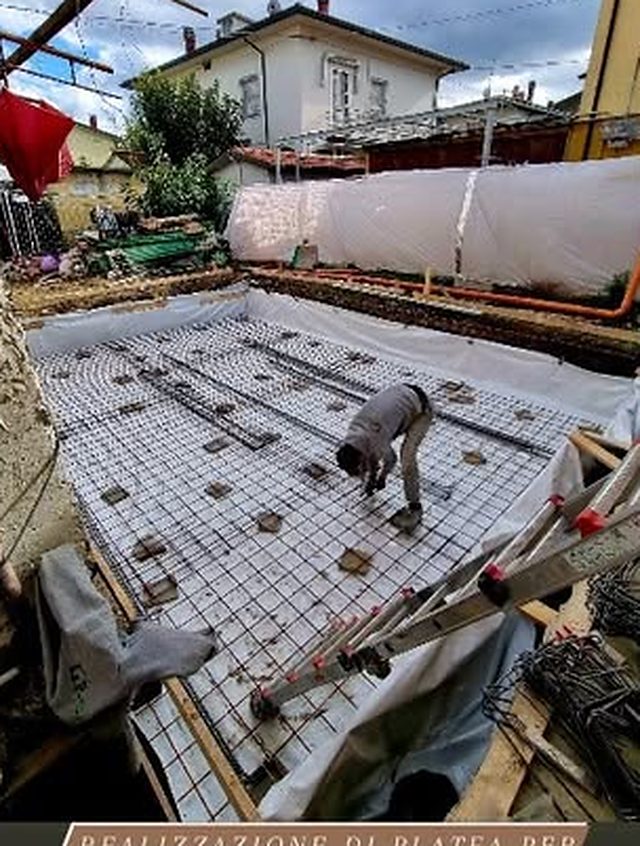 Armatura in ferro predisposta per il getto di una platea in cemento armato, con operaio al lavoro